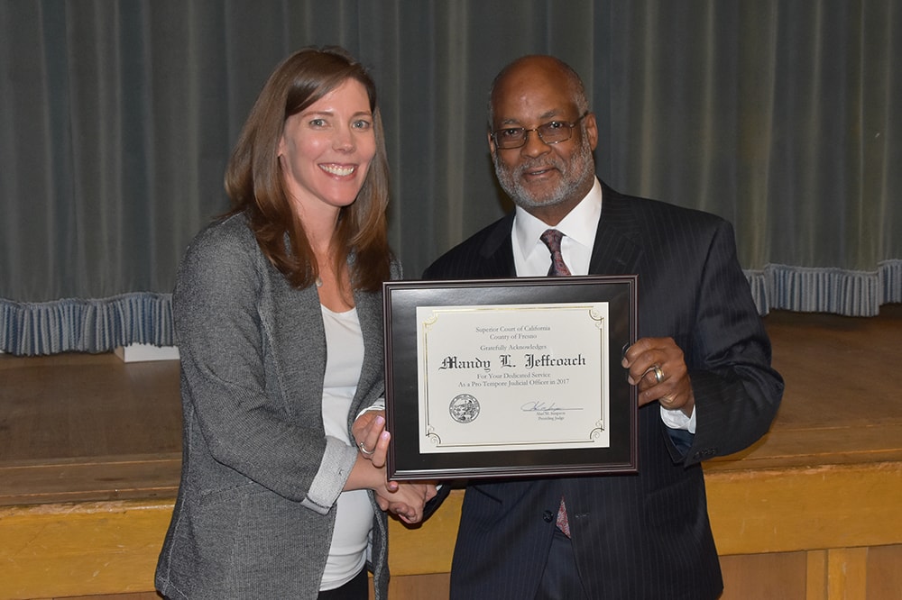 Mandy Jeffcoach poses with an award of recognition for pro bono service during a Fresno County Bar Association luncheon.